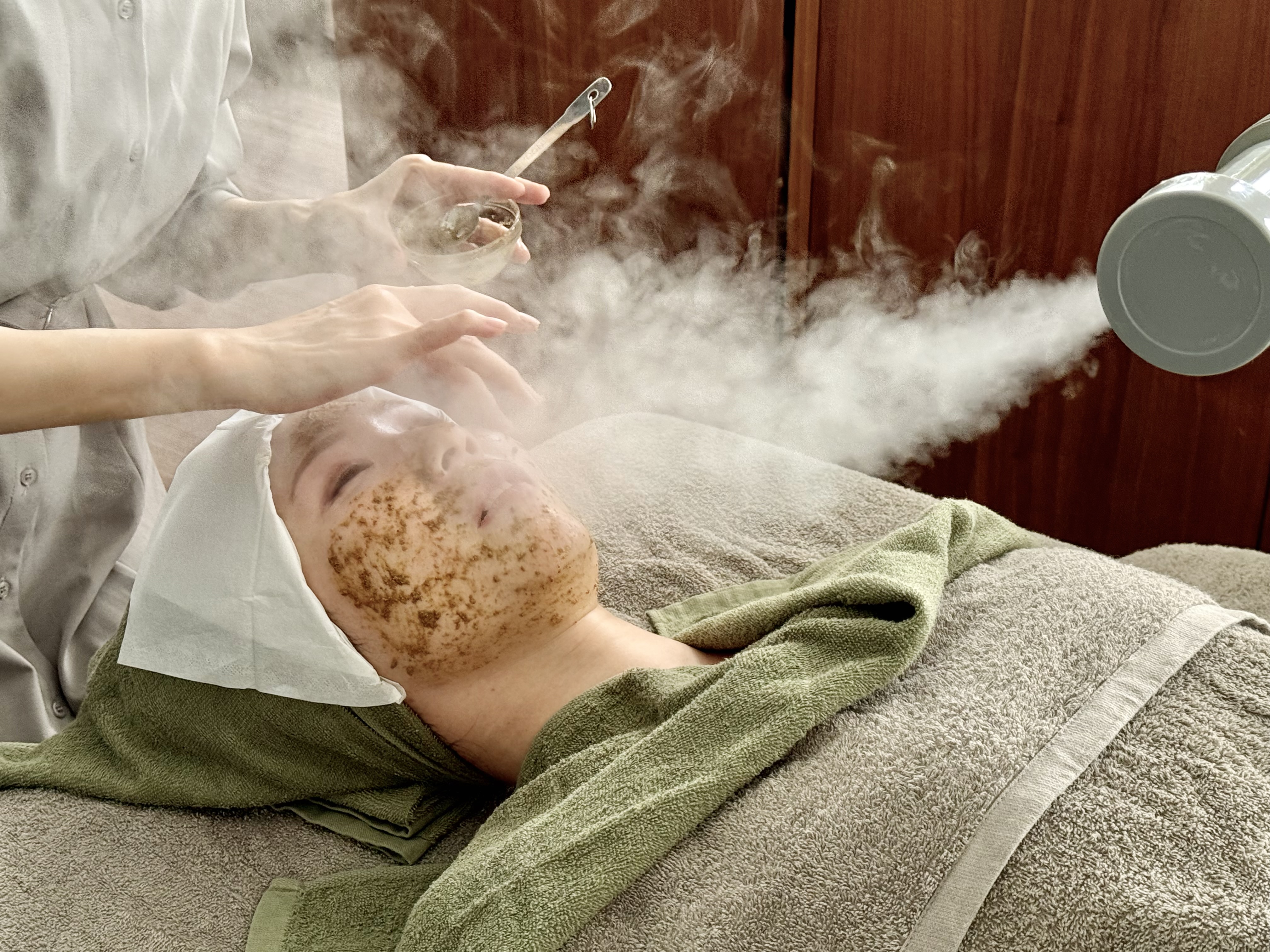 Eye-level view of a skincare professional applying gentle exfoliation on a client's face